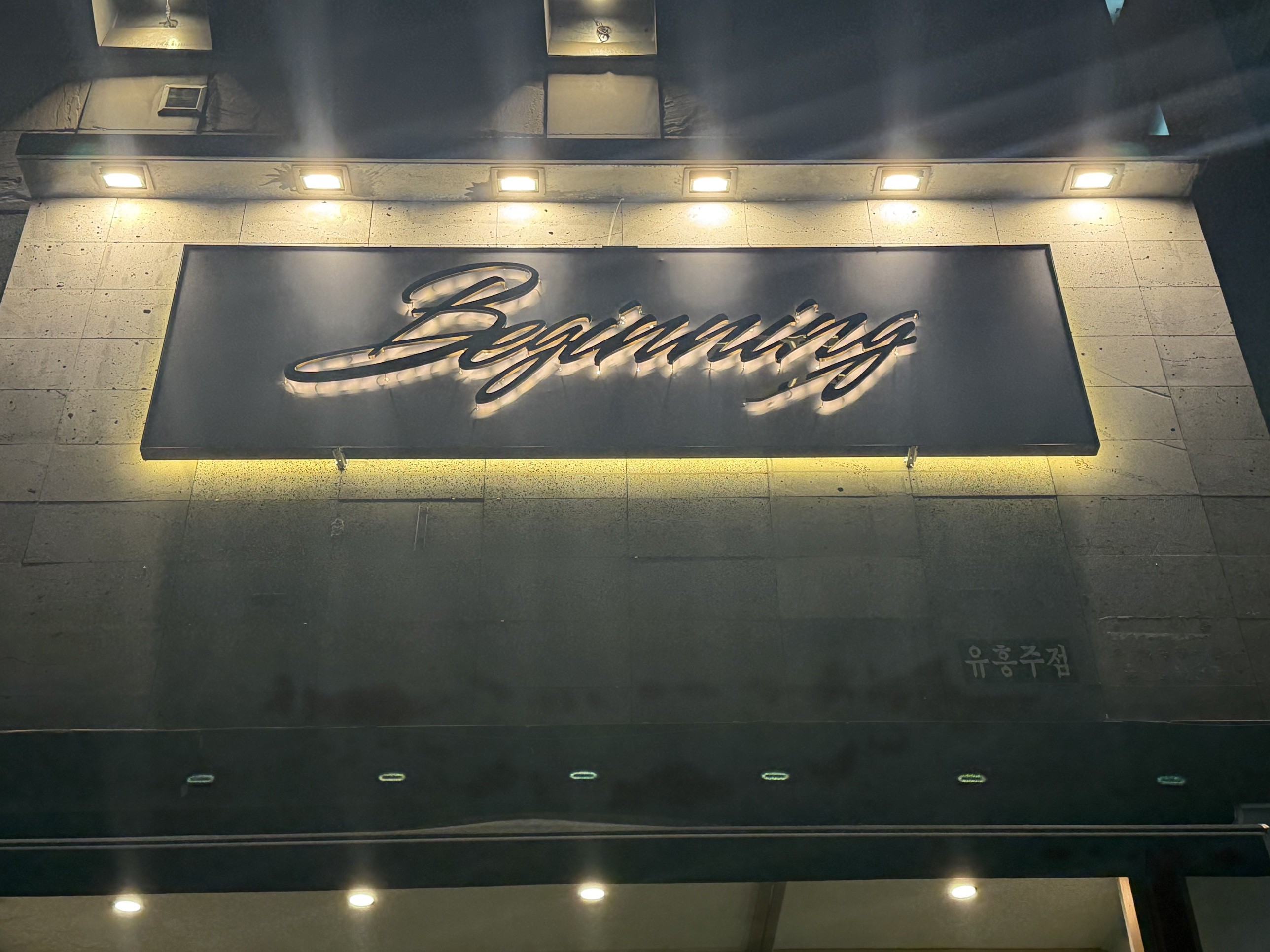 조명이 켜진 필기체 Beginning 간판과 유흥주점 표지, 정면
